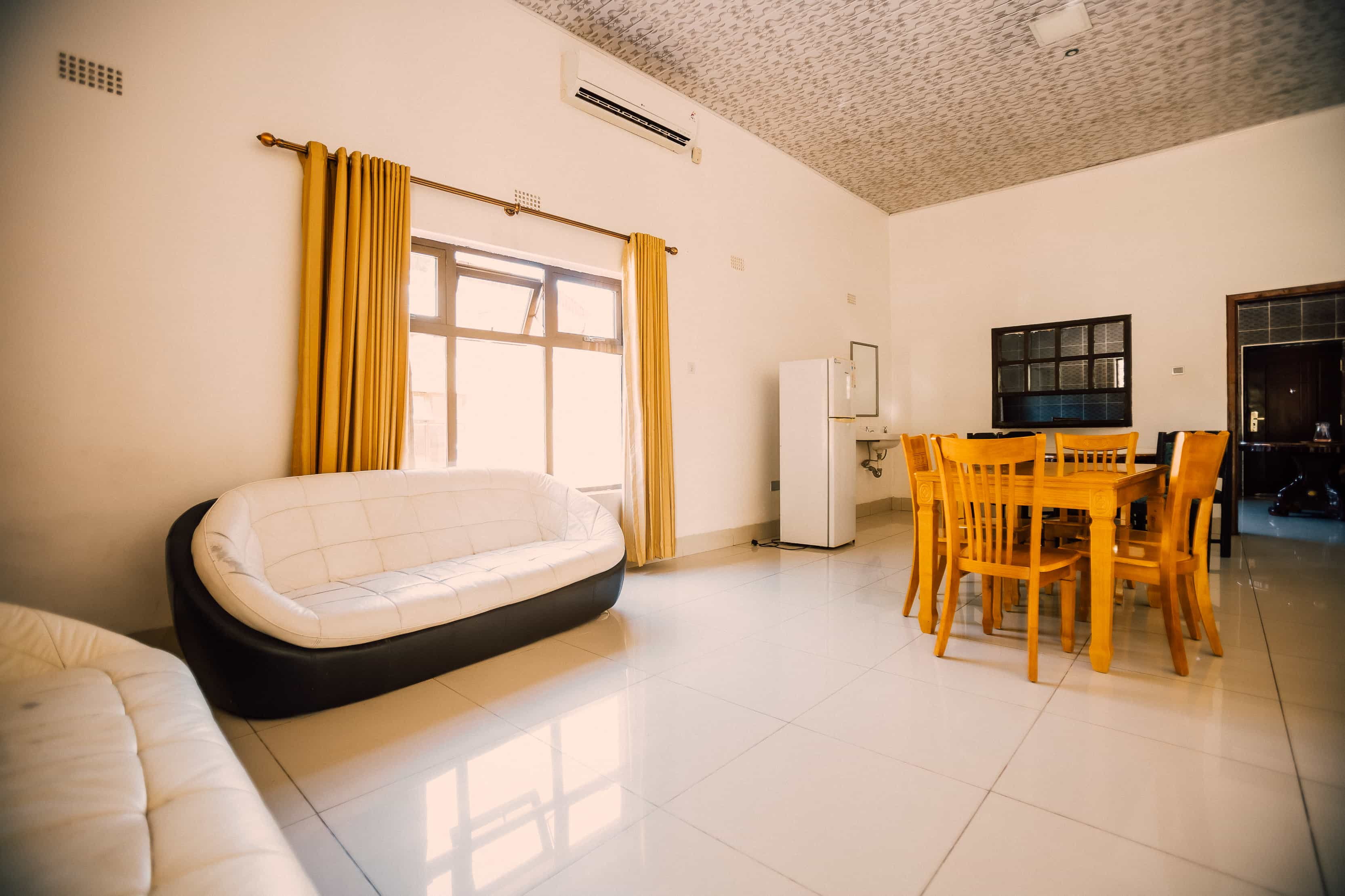 inside view of living room with sofas dining table and fridge