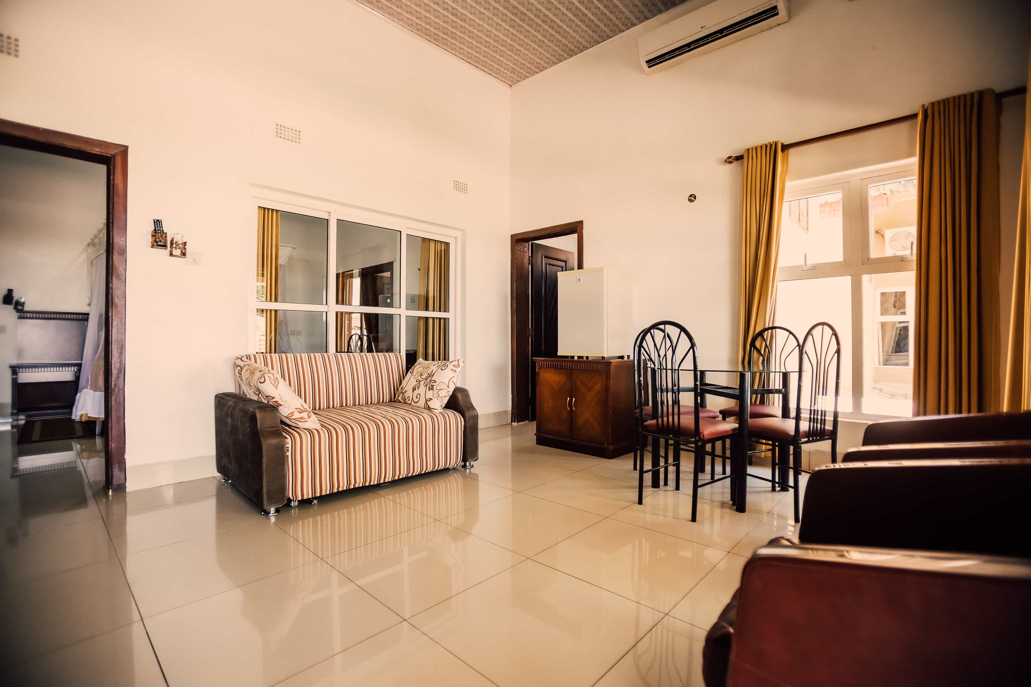 inside view of room from entrance with sofa mini fridge dining table and room door in view